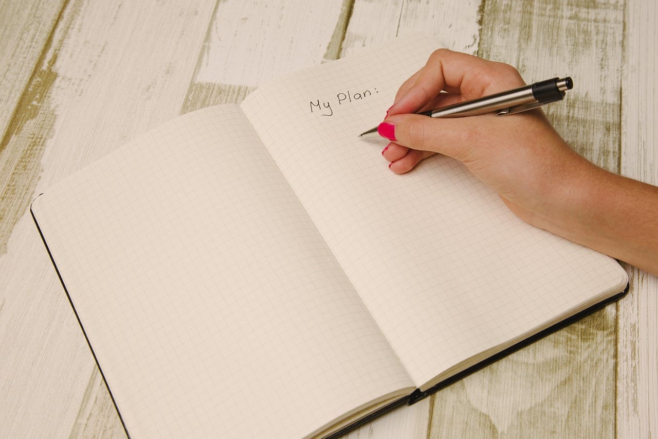 A hand writing My Plan in a notebook
